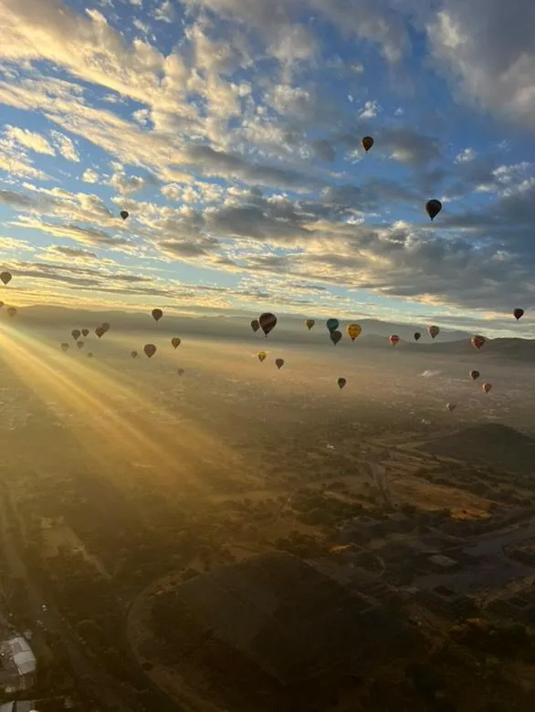 Los rayos del amanecer atraviesan la neblina del valle de Teotihuacan mientras decenas de globos aerostaticos se elevan sobre las piramides