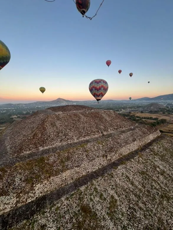 Varios globos aerostaticos flotando sobre la piramide del Sol de Teotihuacan durante el amanecer